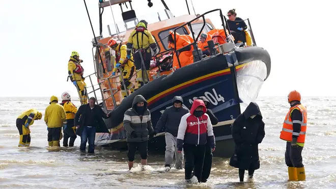 Channel migrants are pictured being escorted from a Border Force rescue boat on Thursday