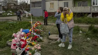 Women cry next to a memorial for the victims who died during Friday’s Russian attack on a residential building in Uman, central Ukraine