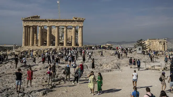 Tourists visit the Acropolis hill with the 2,500-year-old Parthenon temple on the left, and the ancient Erechtheion temple on the right, in Athens, Greece