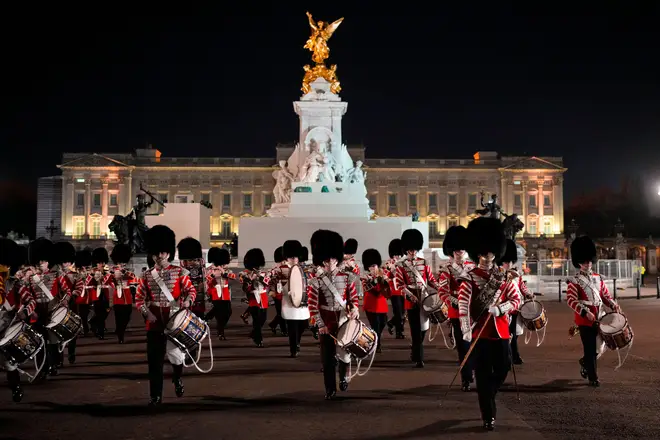 Members of the military band march backdropped by Buckingham Palace in central London