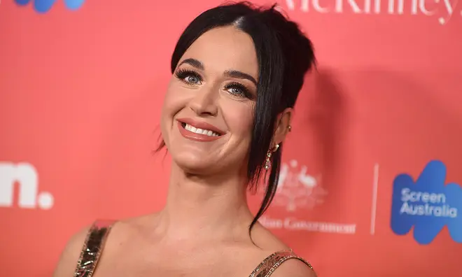 Katy Perry smiling with her hair up and wearing a gold dress