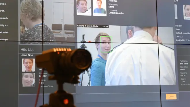 A facial recognition camera in front of a big screen