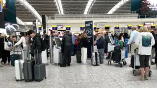 Passengers wait to check in at Heathrow Airport