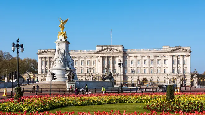 Buckingham Palace on a beautiful sunny day surrounded by blooming red tulips