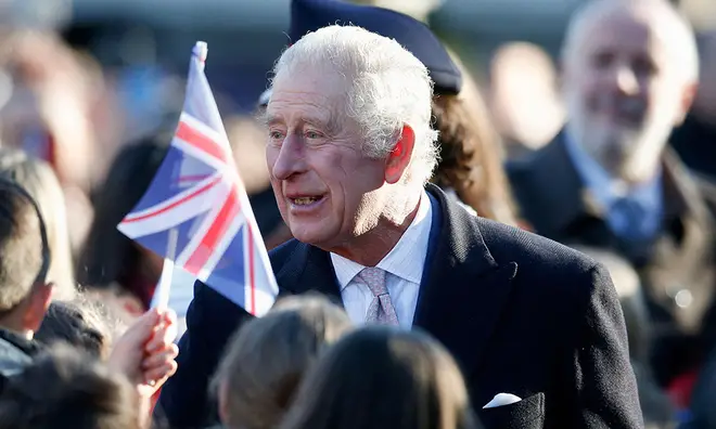 King Charles greeting UK crowds ahead of his coronation day wearing a black blazer and pink tie