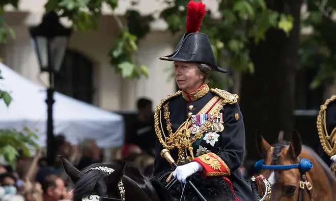 Princess Anne in full military uniform riding on a black horse