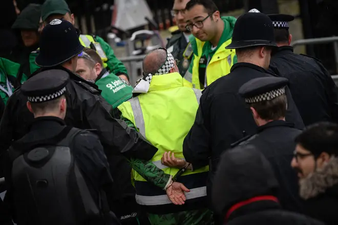 Police officers make an arrest close to the 'King's Procession', a journey of two kilometres from Buckingham Palace to Westminster Abbey in central London