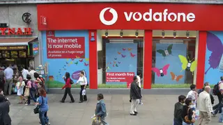 Shoppers walk past a Vodafone shop in Oxford Street, London