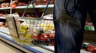 A person holding a shopping basket in a supermarket
