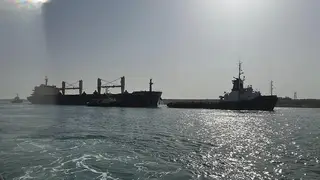 The bulk carrier ship Xin Hai Tong 23, left, is towed after running aground at the southern mouth of the Suez Canal