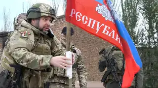 Denis Pushilin, head of the Russian-controlled Donetsk region, sets a Russian-controlled Donetsk region flag atop of a damaged building in Bakhmut, Ukraine