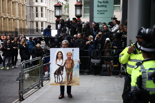 Political satire artist Kaya Mar holds a painting portraying Britain's Prince Harry, Duke of Sussex, and his wife Meghan