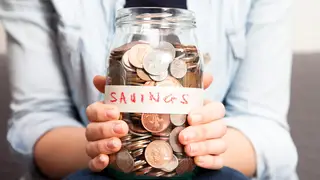 A woman holding a savings jar full of coins