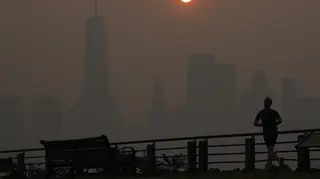 A man runs in front of the sun rising over the lower Manhattan skyline on Thursday