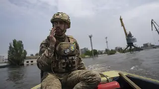 A Ukrainian serviceman steers a boat in a flooded neighbourhood in Kherson, Ukraine