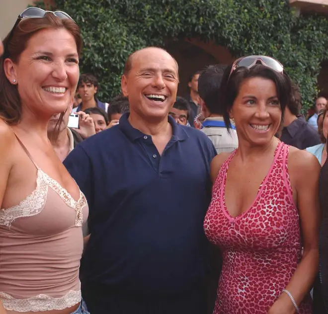 Silvio Berlusconi pictured with two unidentified women as he goes for a walk dressed in a blue shirt and matching pants, outside his luxury villa in Porto Rotondo, Sardinia island, Thursday Aug. 19, 2004