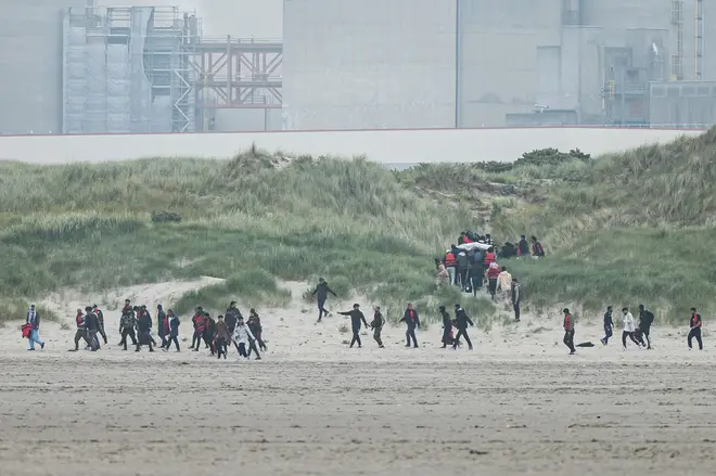 Migrants run up the dunes near Gravelines Nuclear Power Station to hide the smuggling boats from French National Police dispatched to prevent them from illegally crossing the English Channel