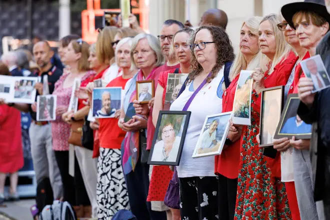 People stood outside the hearing at Dorland House in London with photos of lost loved ones.