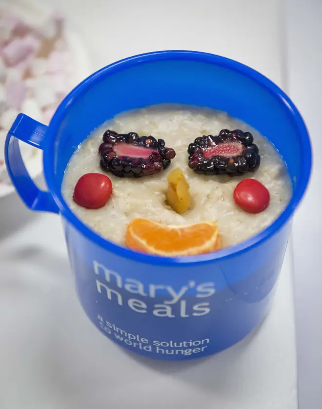 A Mary's Meals cup of porridge with fruit smiley face