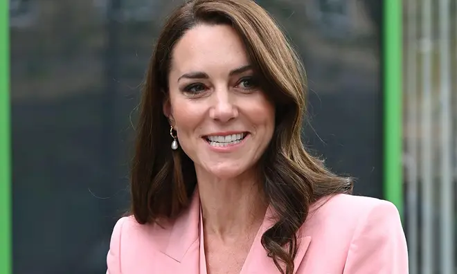 Kate Middleton smiling while wearing a baby pink suit