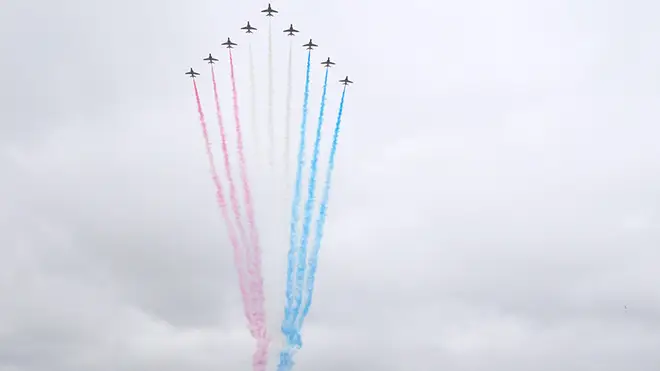The Red Arrows emitting red, white and blue smoke above huge crowds outside Buckingham Palace