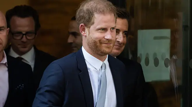Prince Harry dressed in suit and tie smiling as he leaves UK court