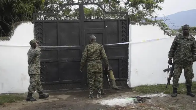 Security forces are seen standing at the premises of an attack in Mpondwe, Uganda