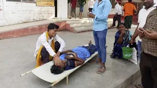 Relatives attend to a patient lying on a stretcher on a hospital site in Ballia district, in northern Uttar Pradesh state