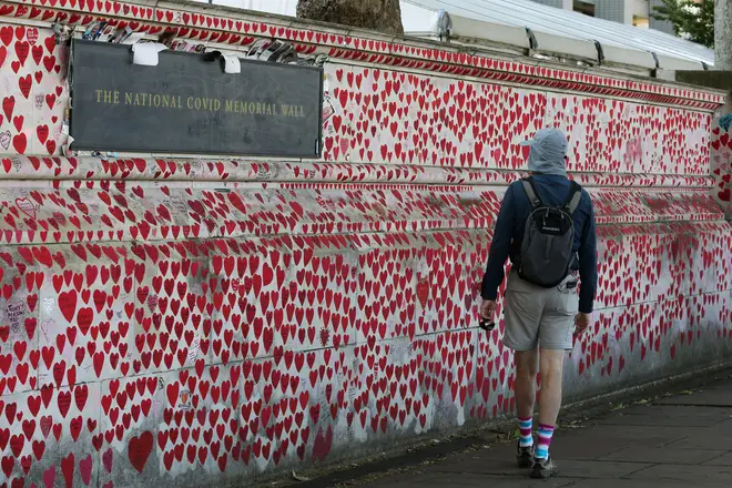 A man walks solemnly past the National Covid Memorial Wall in Westminster, central London