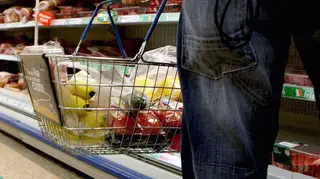 Person holding basket of goods in a supermarket