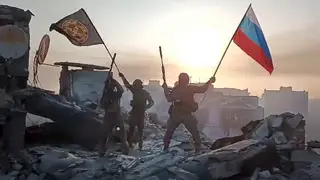 Forces wave Russian and Wagner flags atop a damaged building in Bakhmut, Ukraine (Prigozhin Press Service/PA)