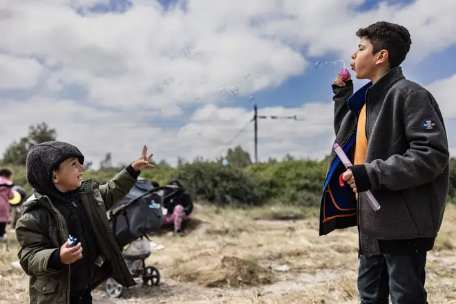 Migrant children blow bubbles at each other 