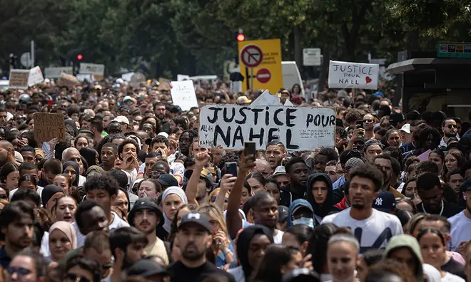 French protests on the streets of Paris with people holding up 'peace for Nahel' signs
