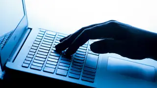 A woman’s hand pressing a key on a laptop keyboard