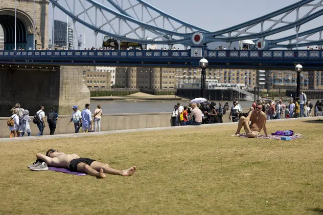 People are seen sunbathing at Tower Bridge area