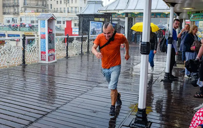 Visitors make a dash for it as they try to escape the torrential rain showers on Brighton Pier