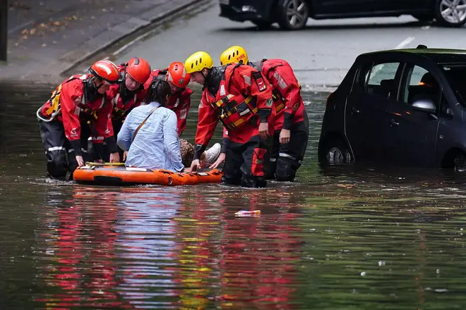 Emergency services rescue a woman from her vehicle after it got stranded on a flooded road