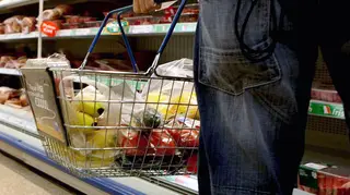 A person holding a shopping basket in a supermarket