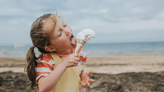 A young girl eating an ice cream on the beach