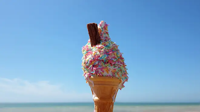 An ice cream with a flake covered in sprinkles on the beach