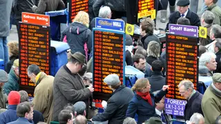 Bookmakers ply their trade as racegoers gather around to place bets