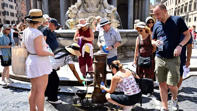 People queue to fill bottle with water at a public tap