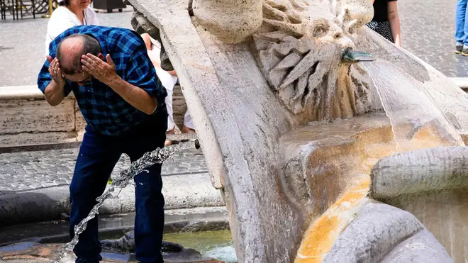 A man refreshes at the Baroque-style fountain 'Fontana della barcaccia' at the foot of the Spanish Steps in Rome's Piazza di Spagna