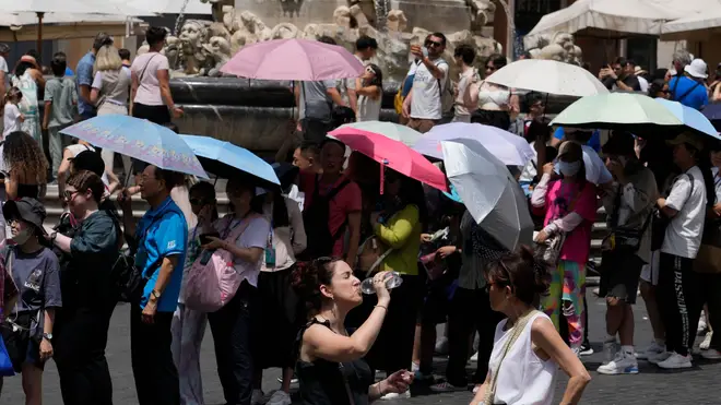 Tourists use umbrellas to shelter from the sun