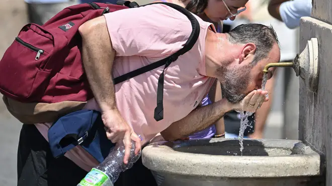 A man drinks water from a fountain