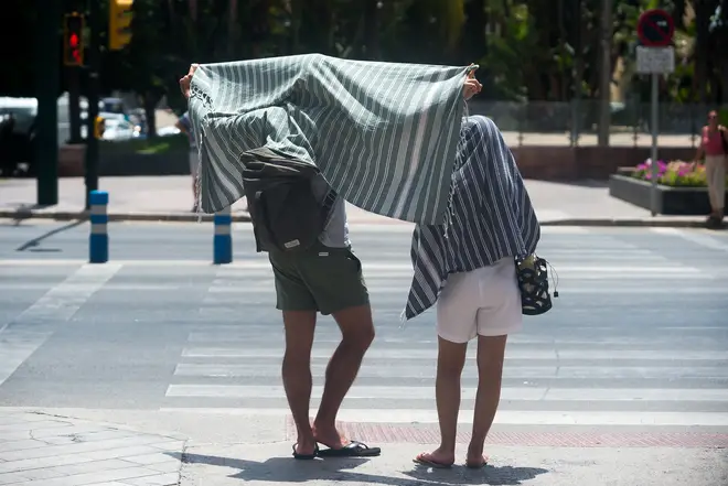 Tourists cover themselves with towels in downtown city amid an intense heatwave in Malaga.