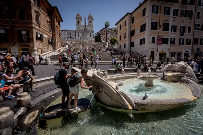 Tourists refresh themselves with water from a fountain in Rome