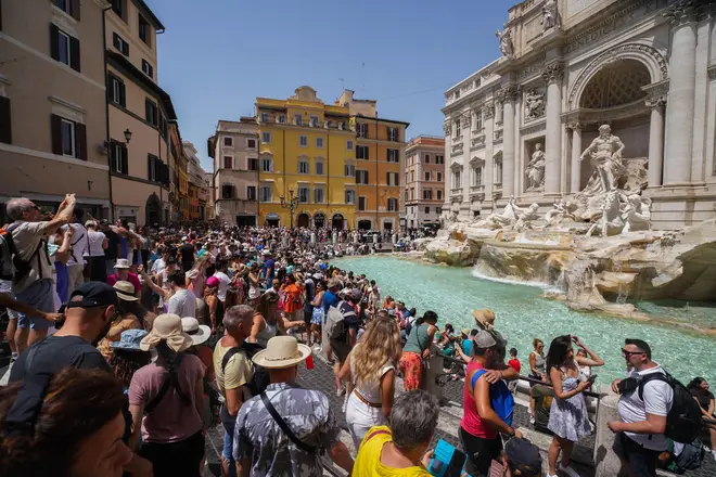 Large crowds of tourists cool off at the Trevi fountain