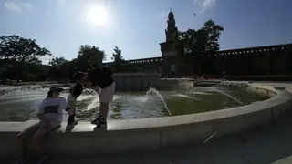 Tourists cool off in a public fountain at the Sforzesco Castle in Milan