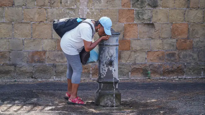 A woman drinking from a water fountain on another sweltering day
